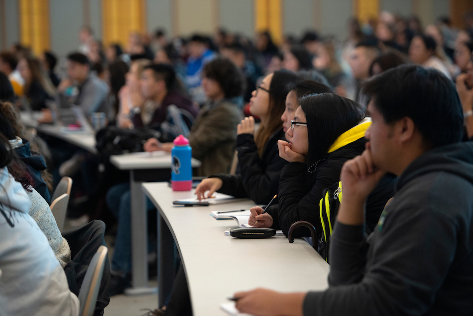 A lecture hall is full of attentive students.