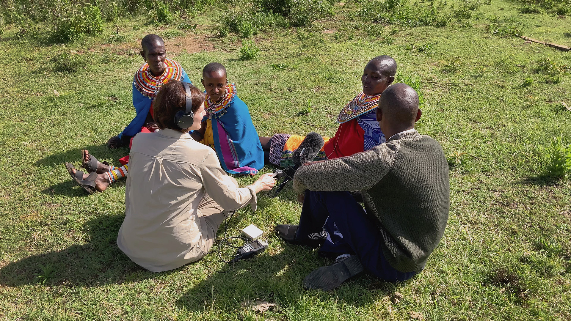 Women in Kenya talk with American woman reporter with microphone