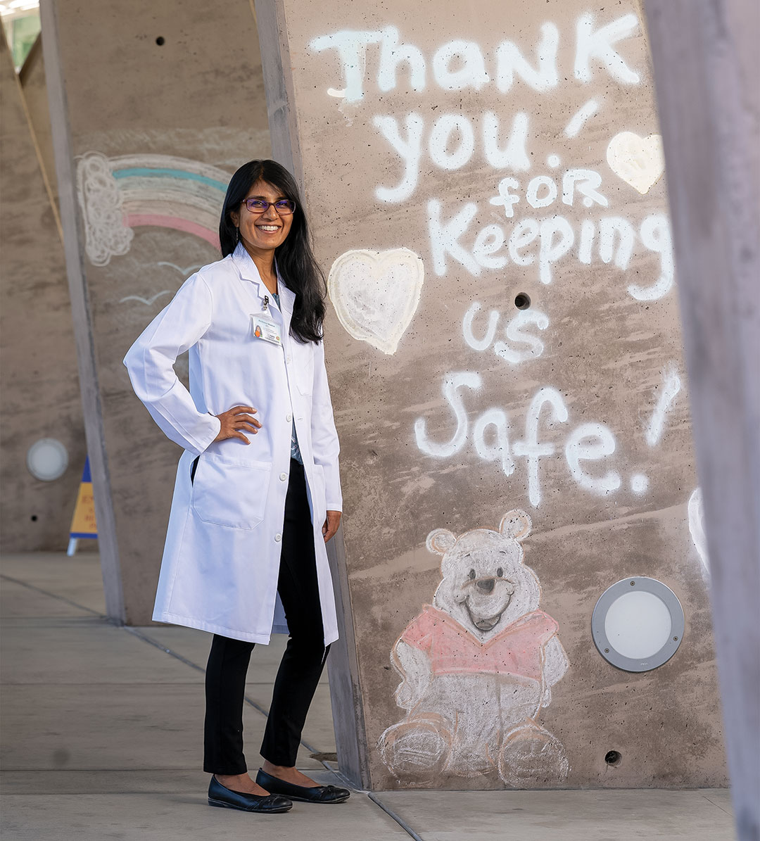 maniar-archana A woman doctor stands by graffiti that says 'thank you for keeping us safe'