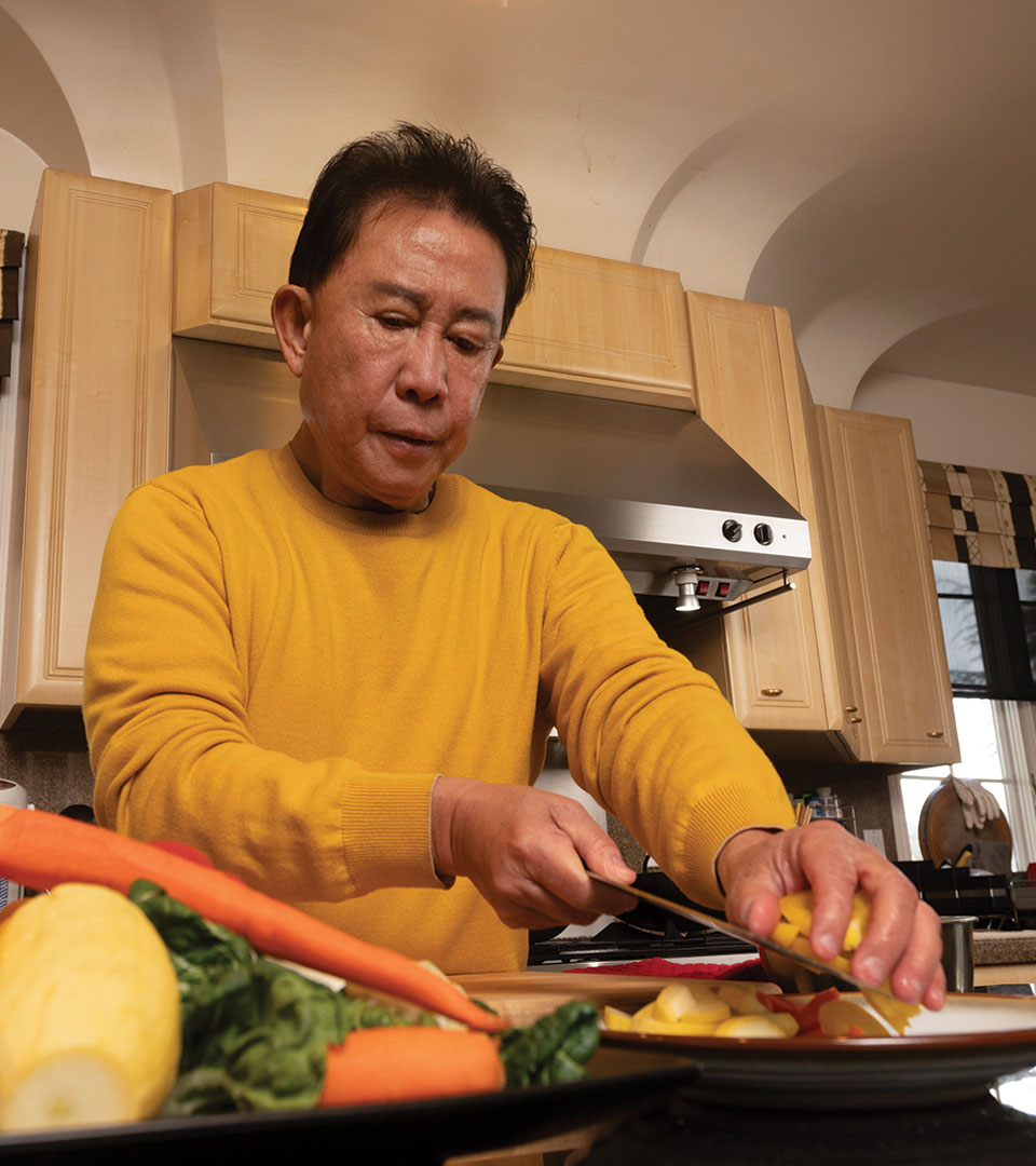 martin-yan-in-kitchen Martin Yan slices vegetables in his home kitchen