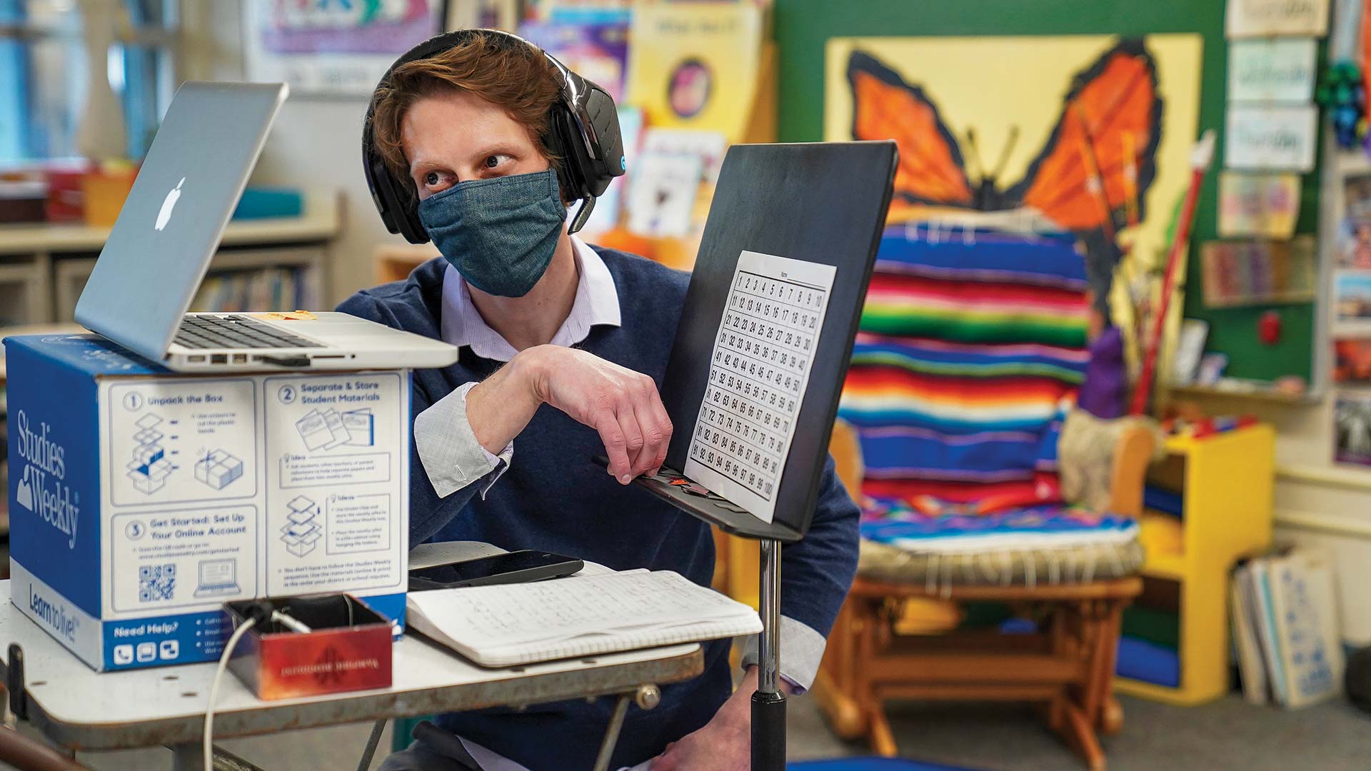 portraits-ushing a man wears a mask and looks ino a computer while teaching