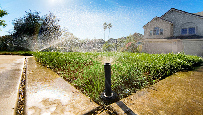 sprinkler-web-700x395 Sprinklers water a lawn in front of a house