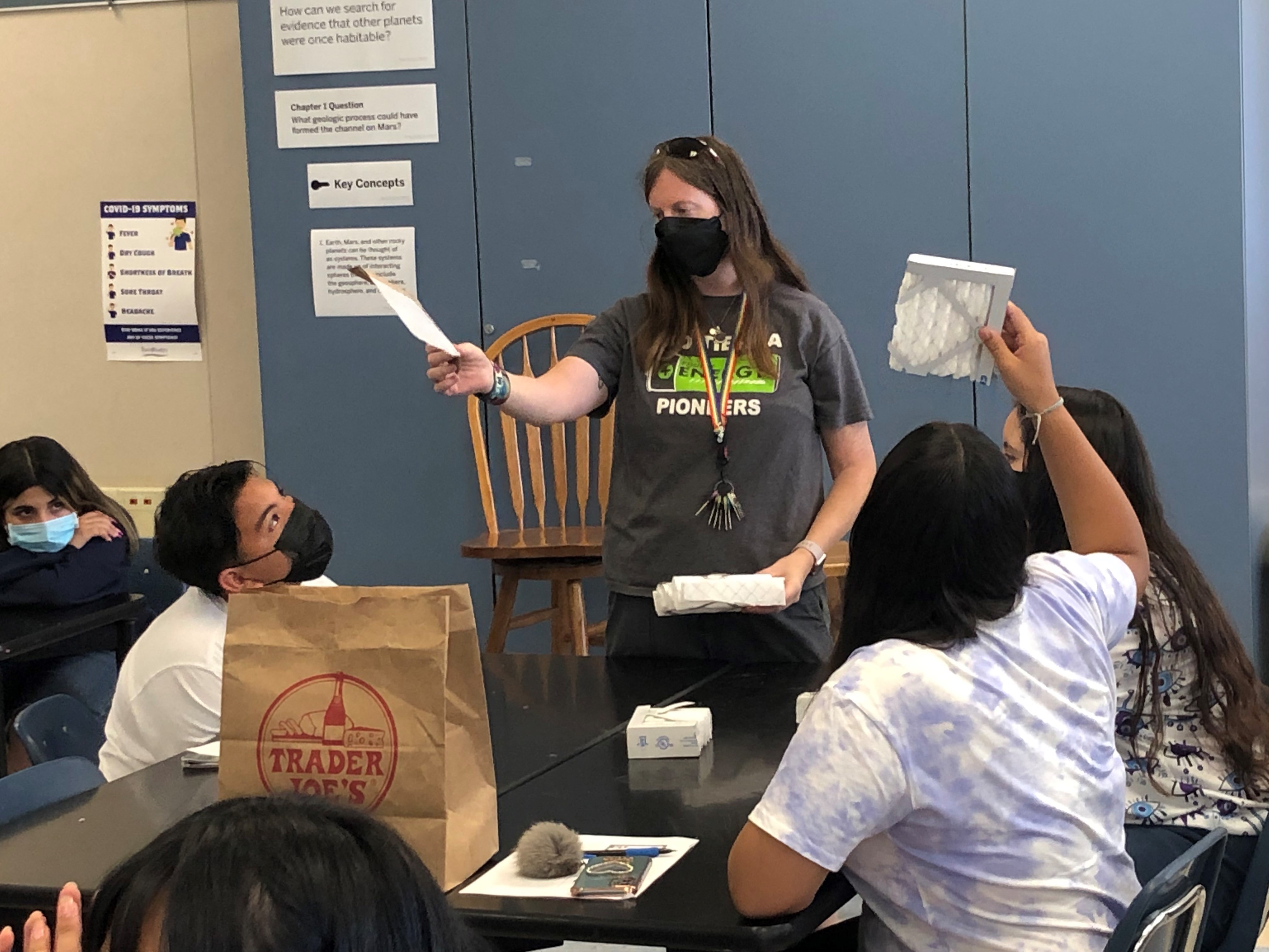 Junior high school teacher with students holding up air filtration panels during a lesson