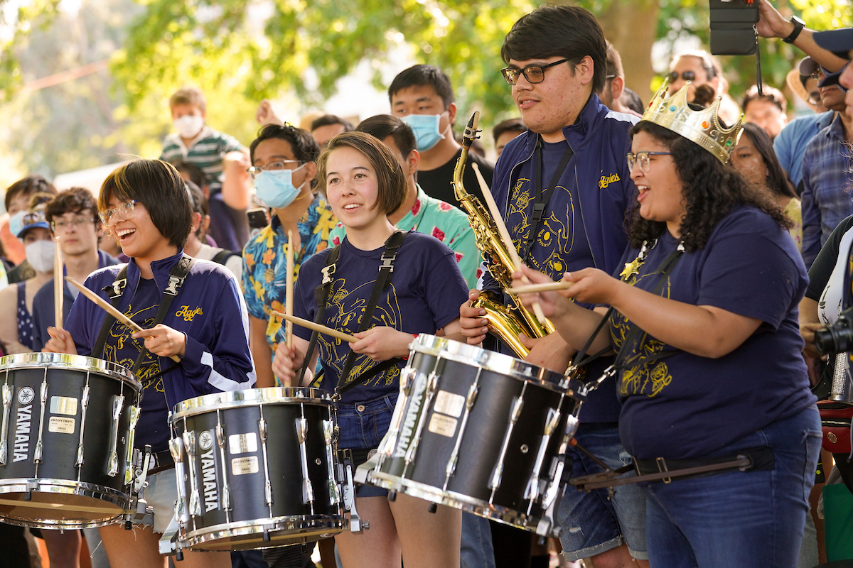 Marching band drummers in navy shirts playing snares and cymbals outdoors (photo)