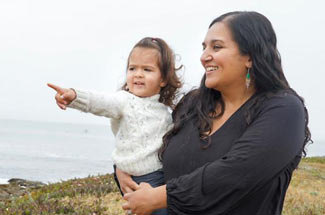 Mother holds toddler at ocean