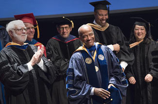 Chancellor May in academic regalia, wearing medal, smiling, at investitureat in