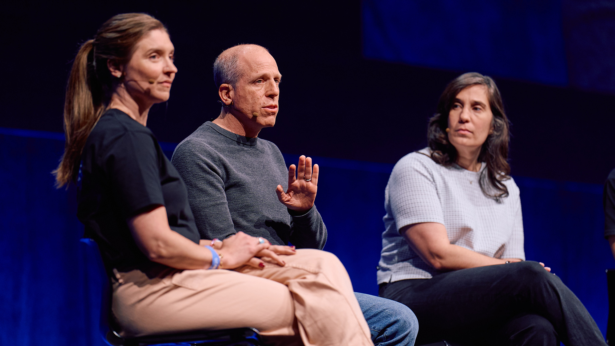 Three people sitting on stage for a conference session