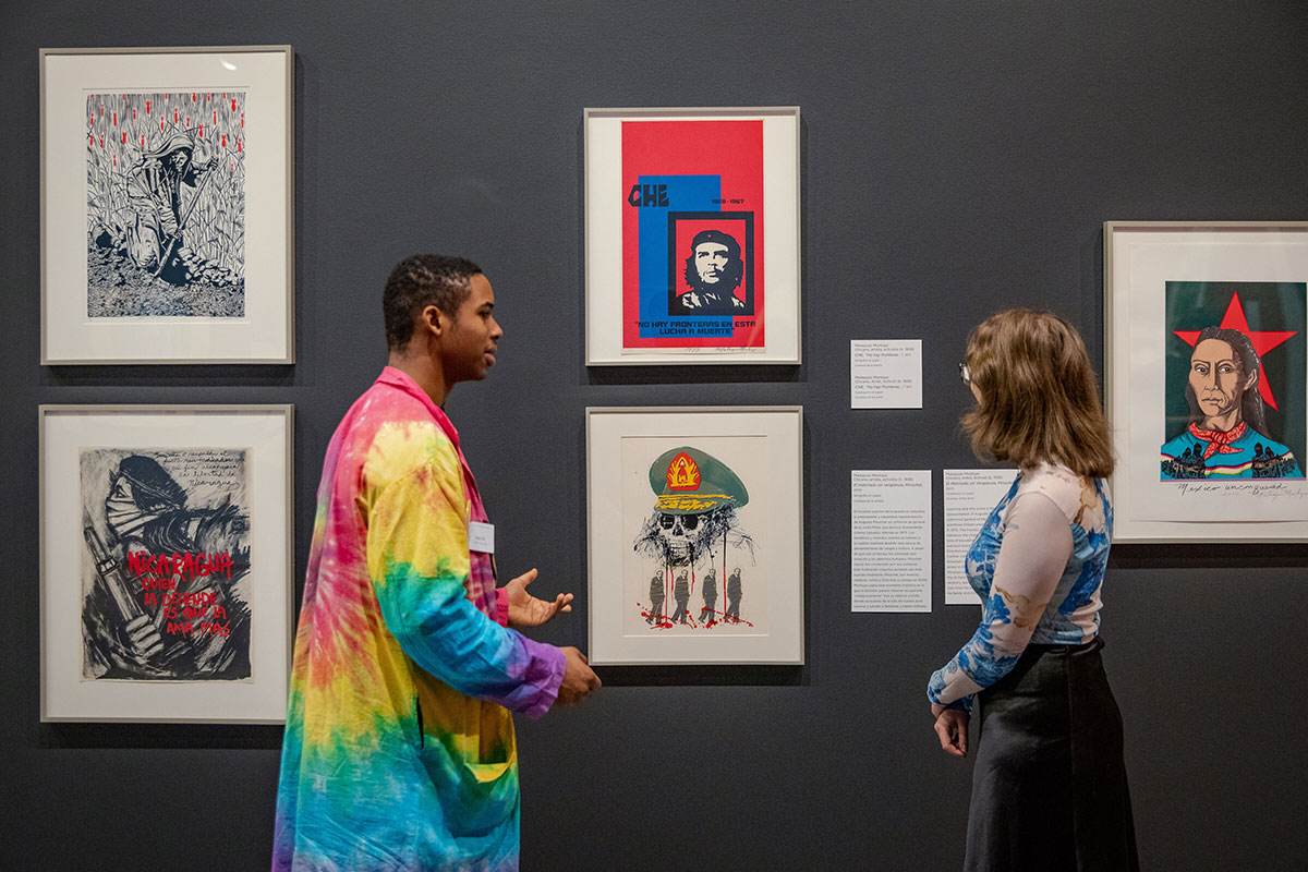 people discussing art in front of prints on wall