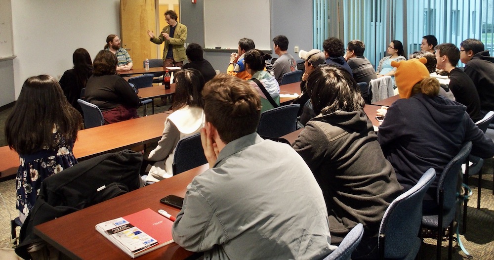 Professor Foster stands in front of a class with a guest presenter at UC Davis. 