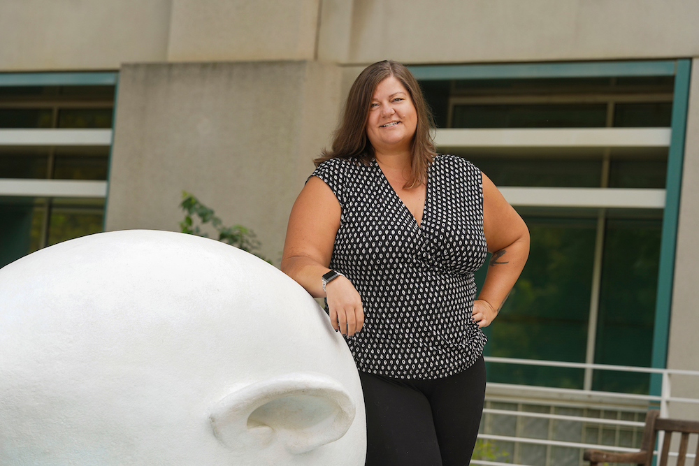 Katy Pattison smiles beside an egghead statue at UC Davis.