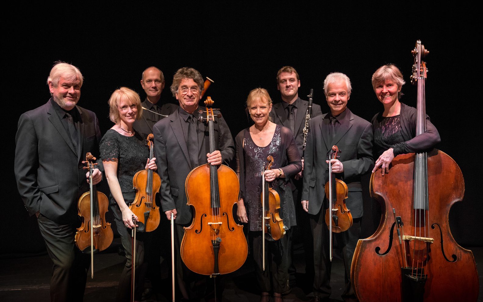 Large group of people standing and some holding instruments 