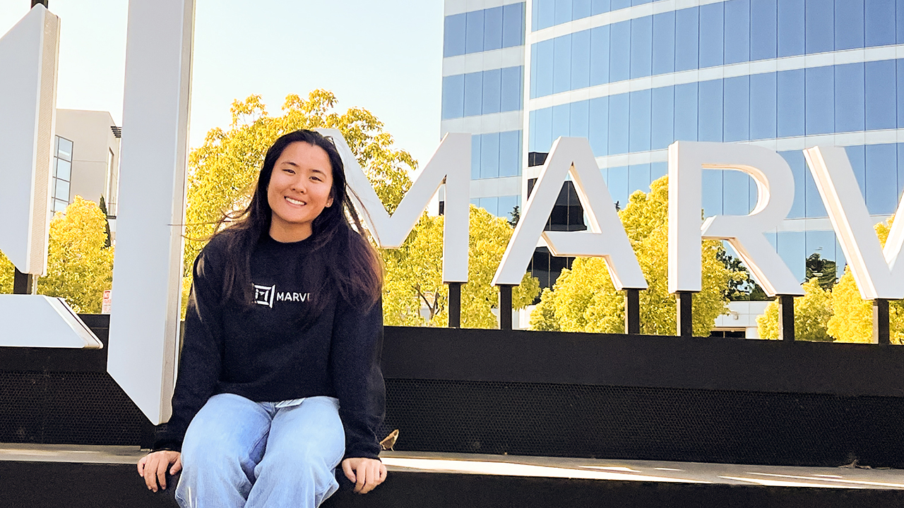 Alexa Kwan sits in front of a company sign for Marvel Technology