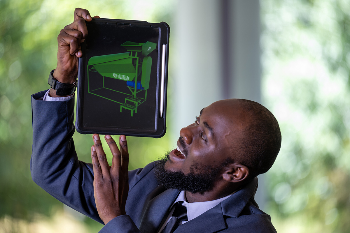 Dark-complected man looking at computer device.