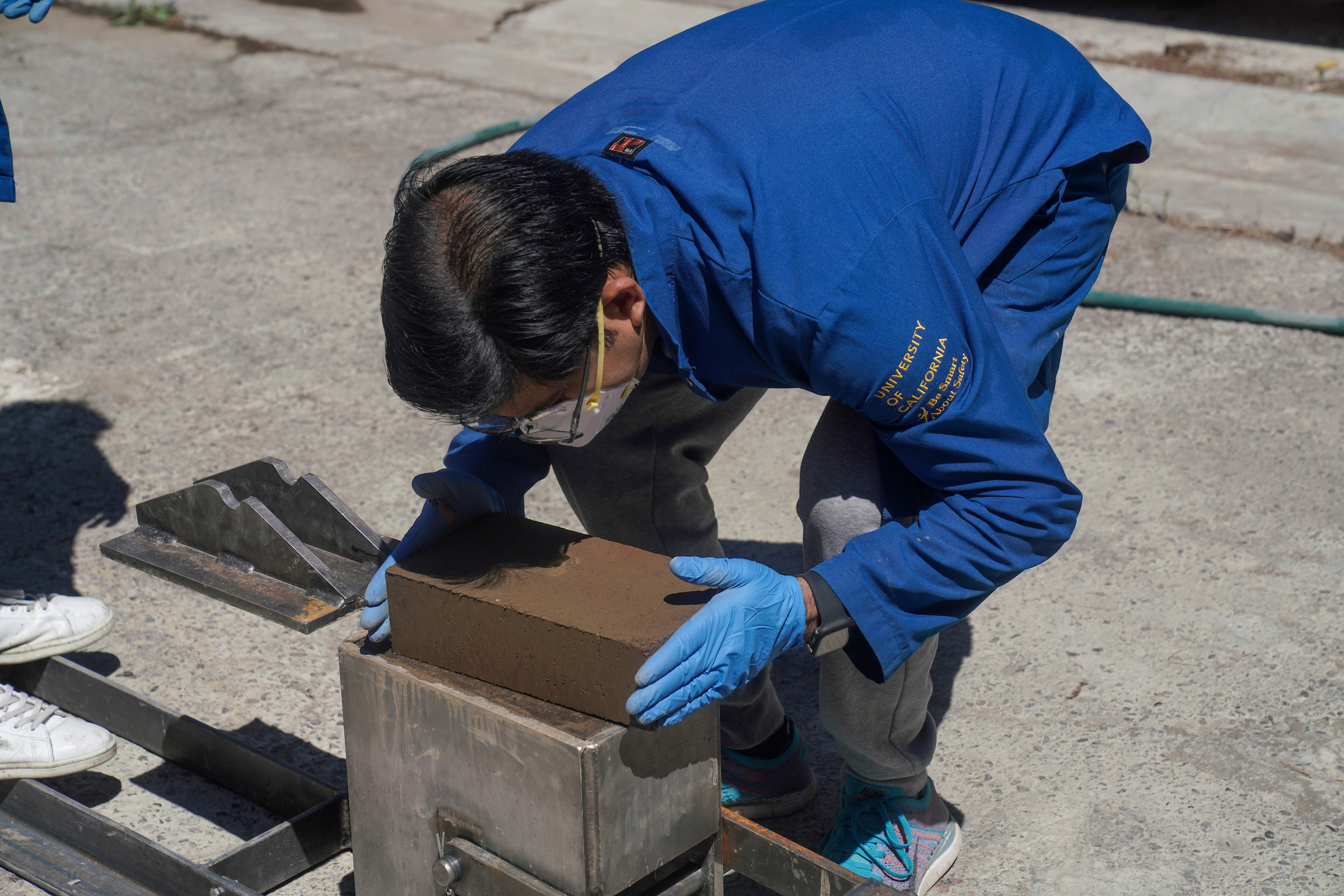 Man is bent over a little block form pulling one out.