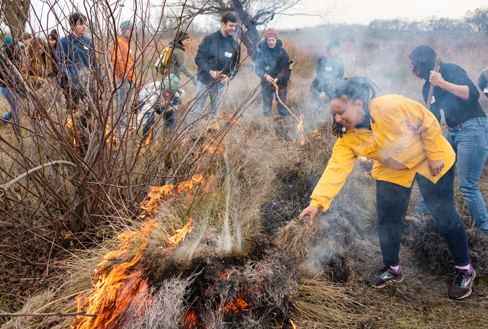 Woman at controlled burn with flames and brush showing