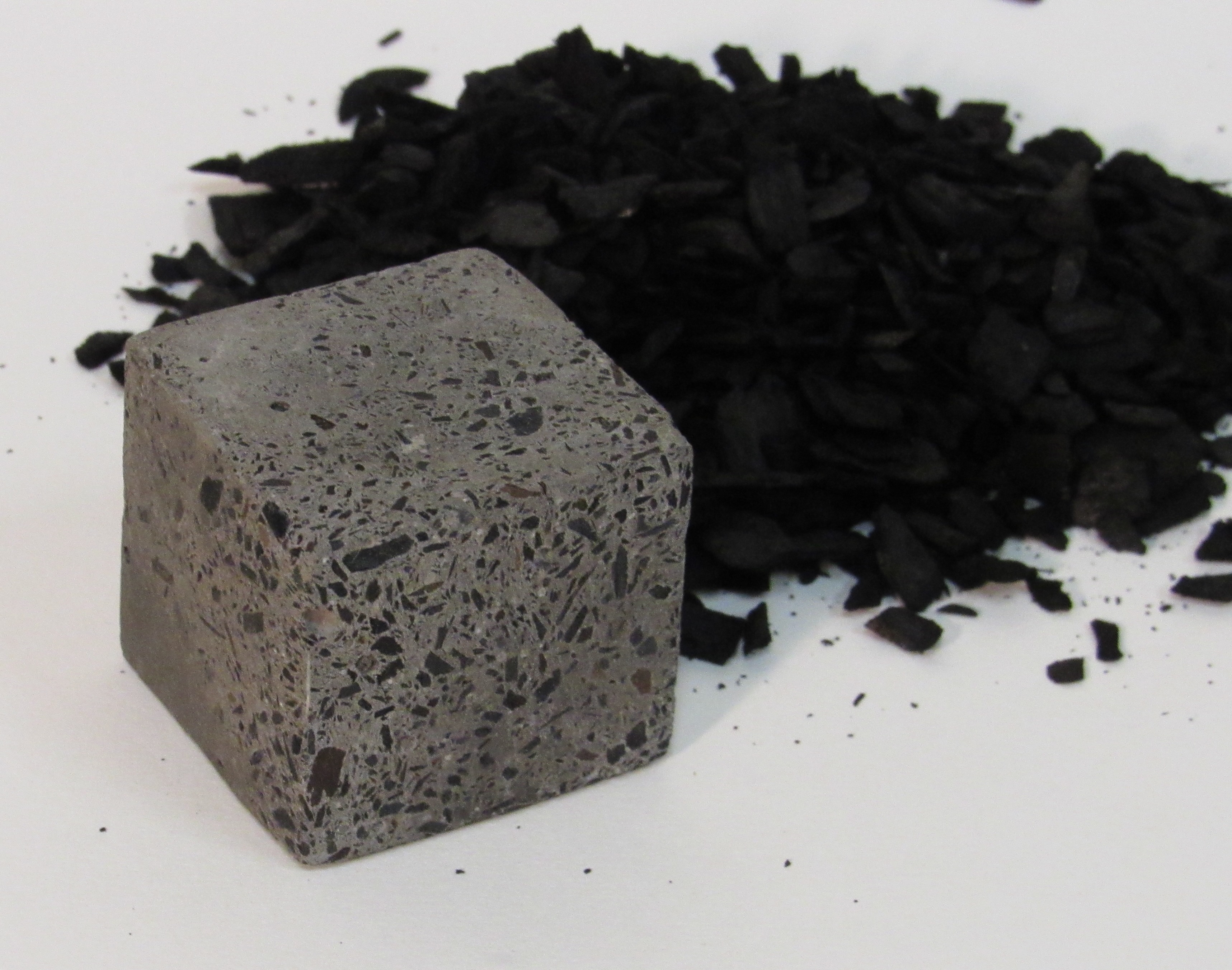 Grey cube with black inclusions next to a pile of black chunky material.