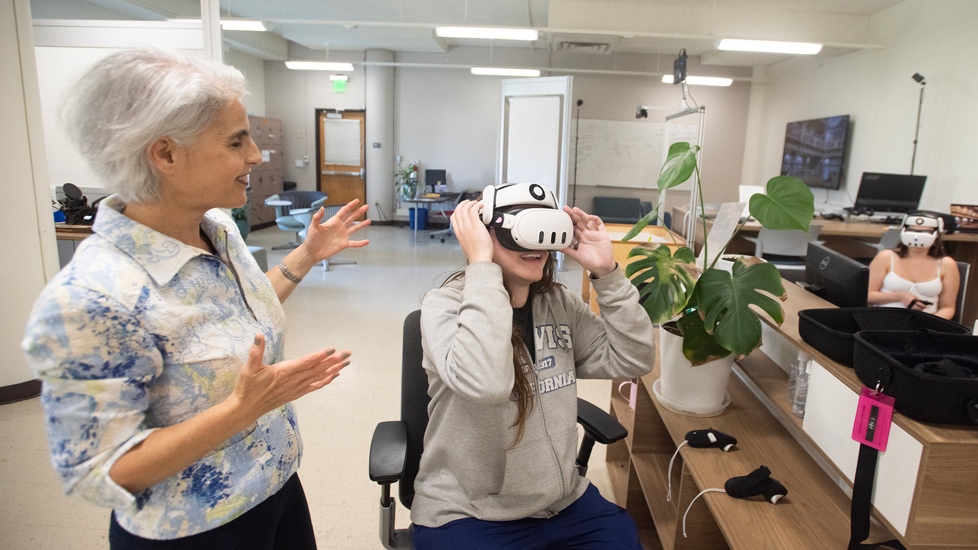 Instructor gestures as student wears VR headset at a desk