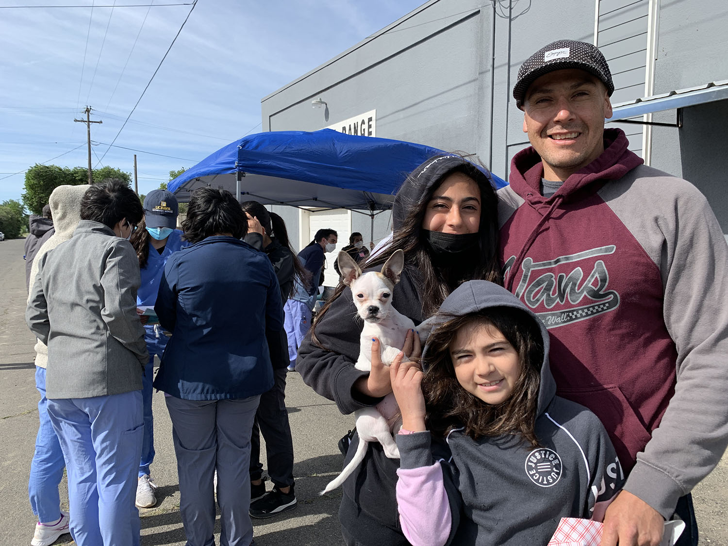 Carlos Ayala, his two daughters, and their chug stand outside the Knights Landing One Health Clinic.