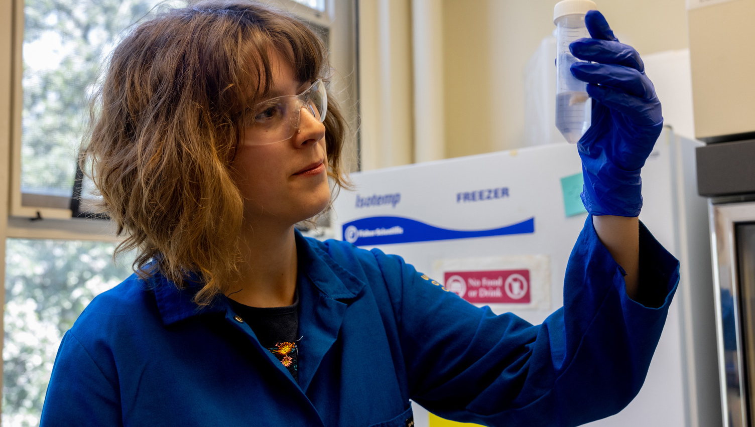 Woman dressed in blue with test tube.