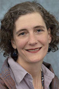 Smiling woman with curly hair, purple shirt and patterned scarf