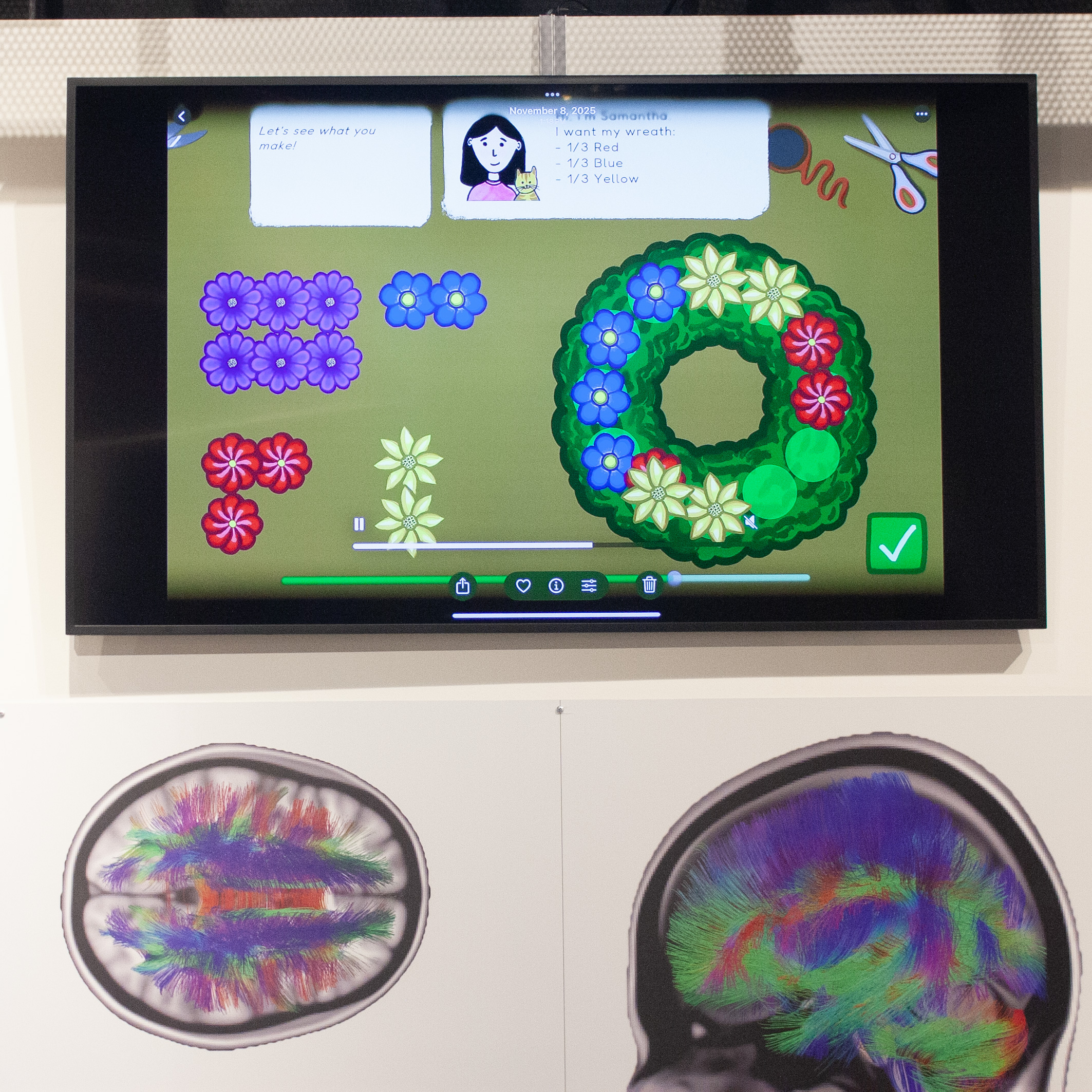 Tablet showing floral wreath game on green background above two color brain scans