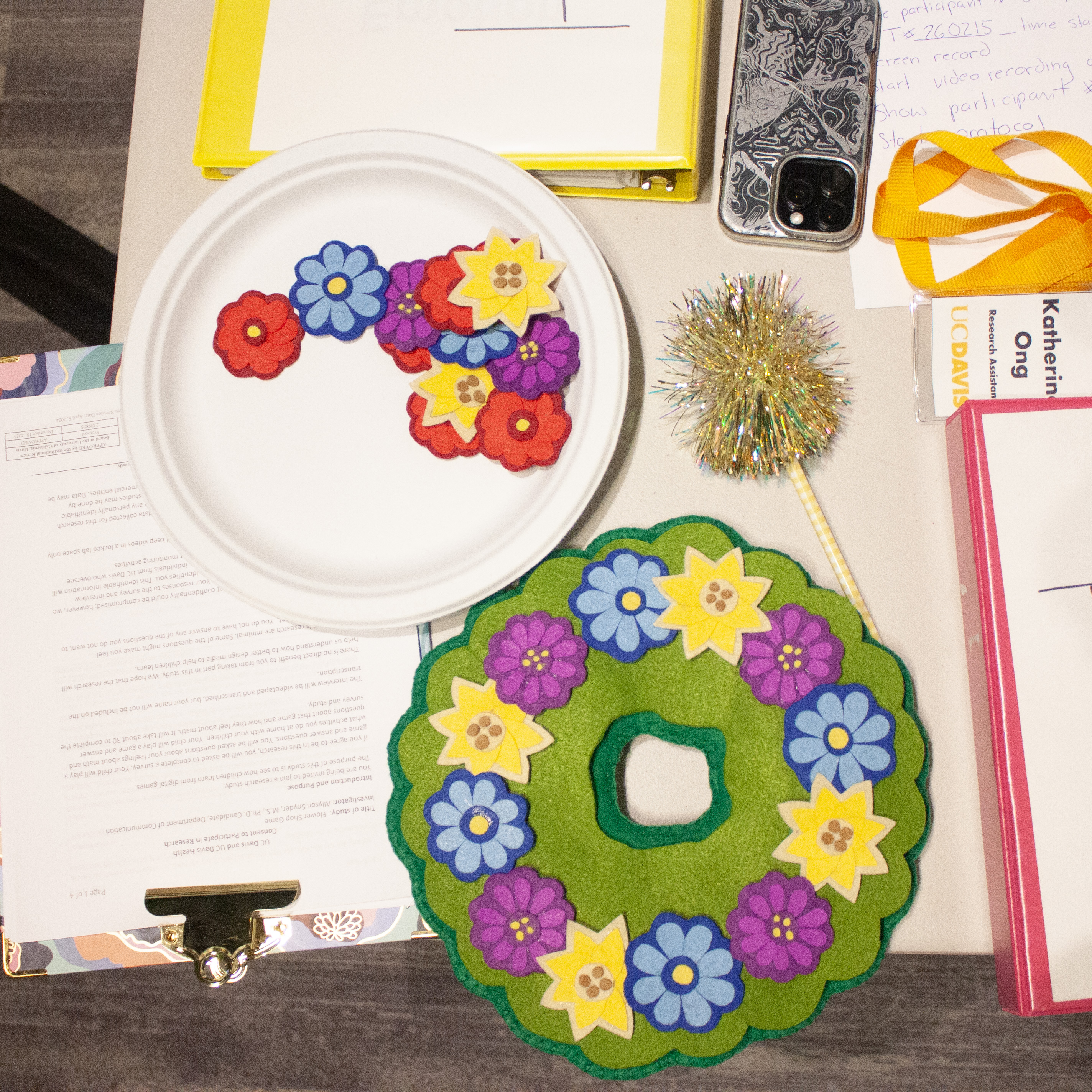 Craft table with green felt flower wreath and extra felt flowers on a paper plate
