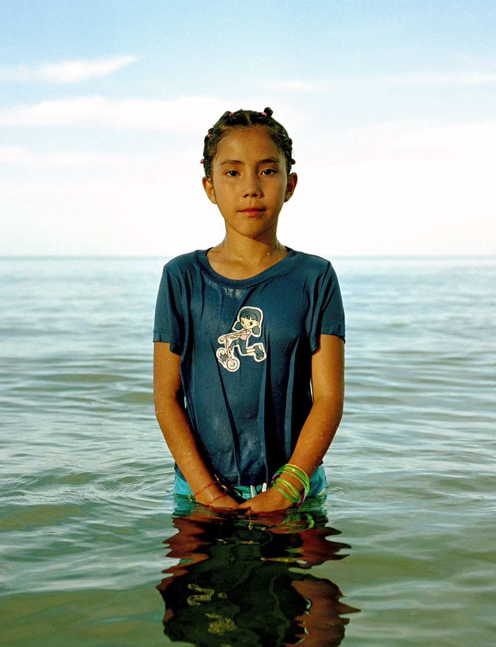 child in body of water with blue sky in background