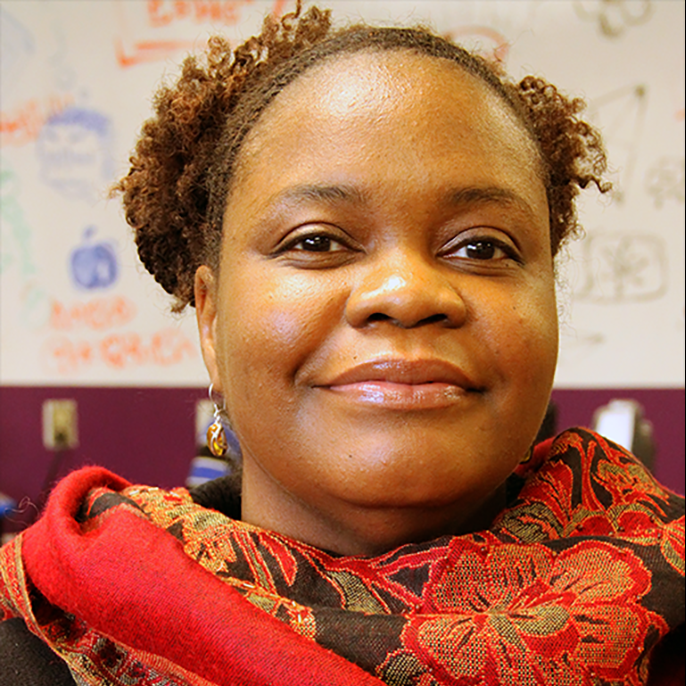 Portrait photo of dark-complected woman wearing orange, patterned scarf