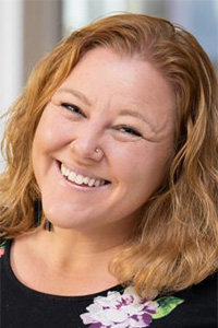 Smiling redheaded woman headshot, wavy hair, floral top