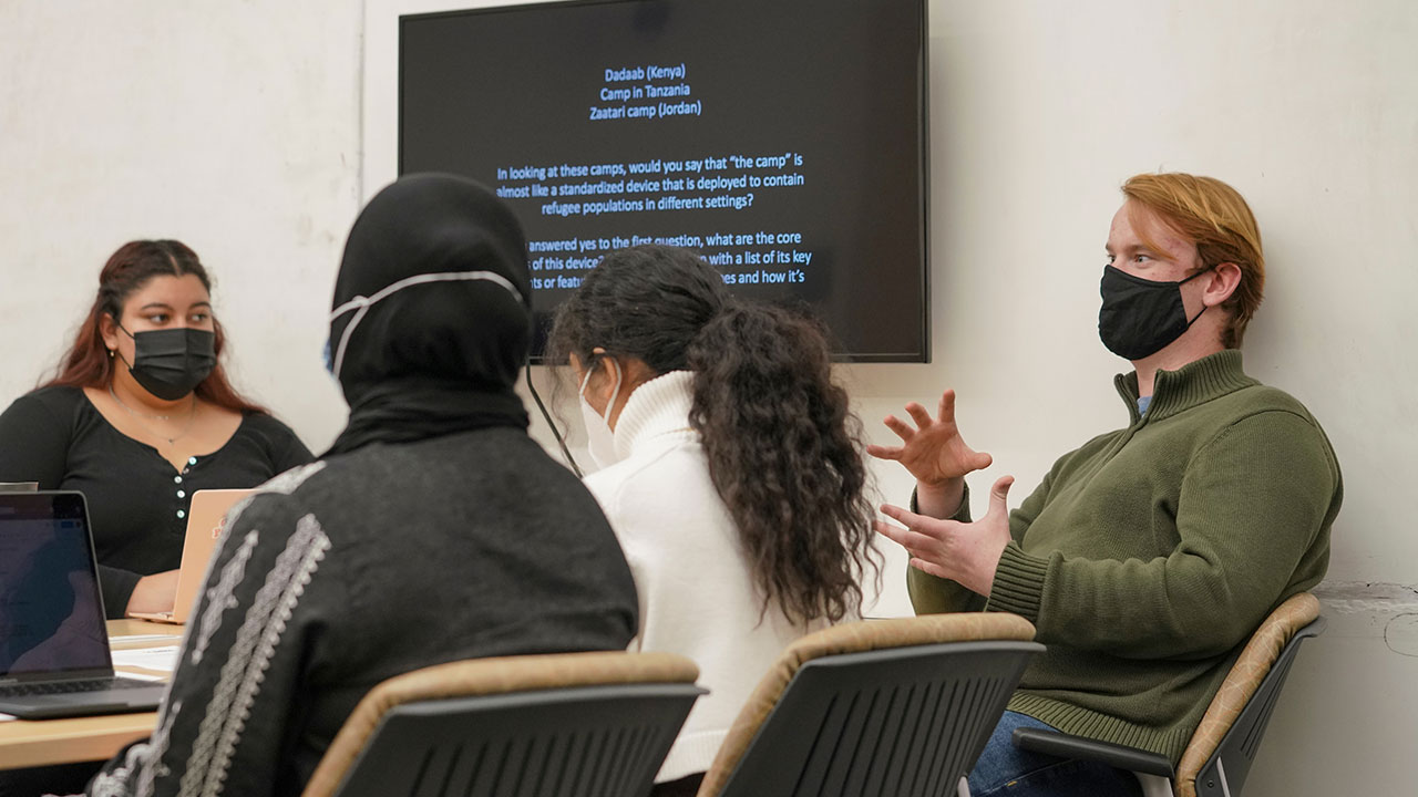 A male student gestures with his hands during a classroom discussion