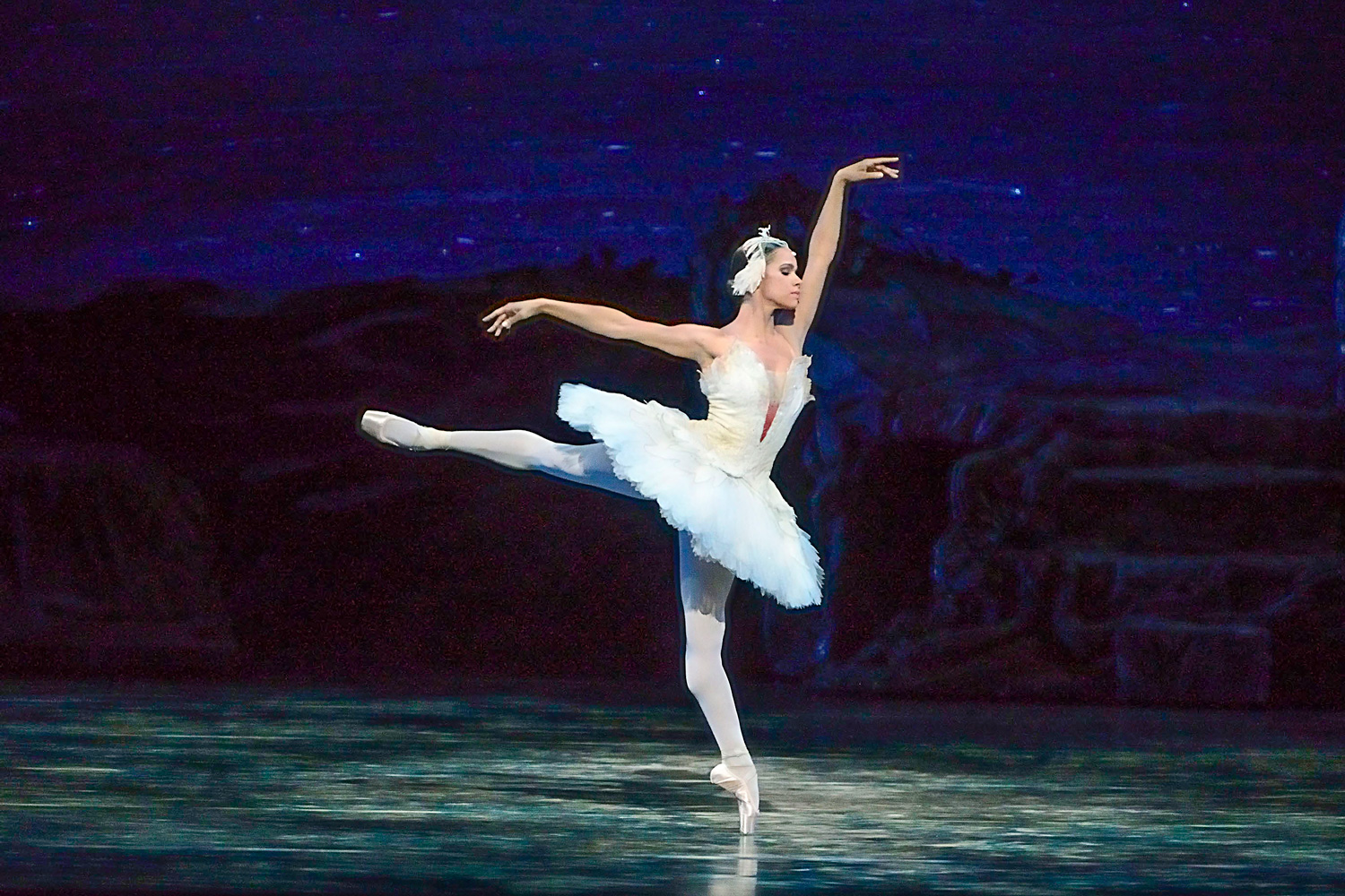 Ballerina Misty Copeland perrforms San Lake on stage in white leotard and tutu, leg and ams extended