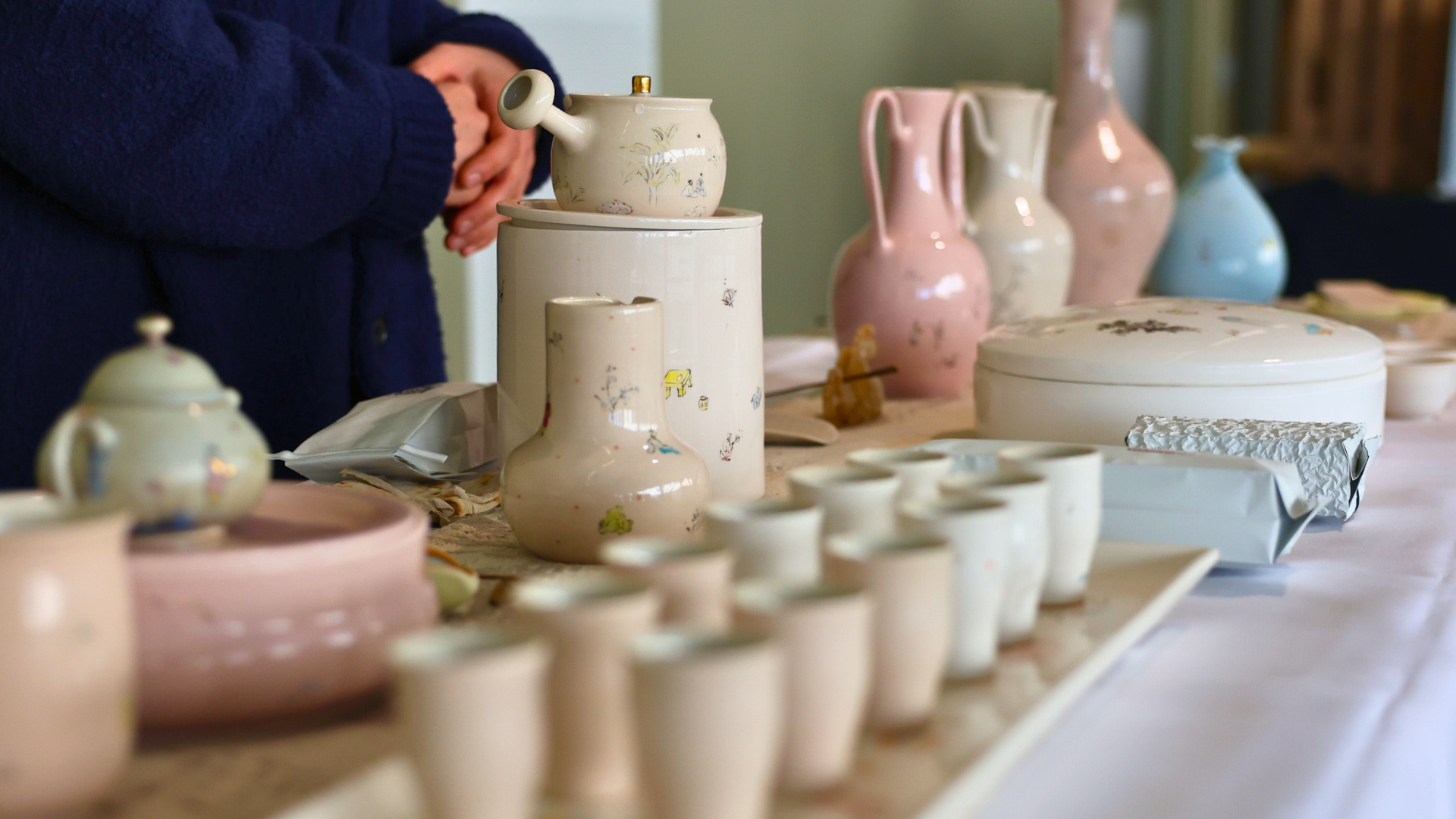 A display of various decorative pottery, including teapots and cups, on a table.