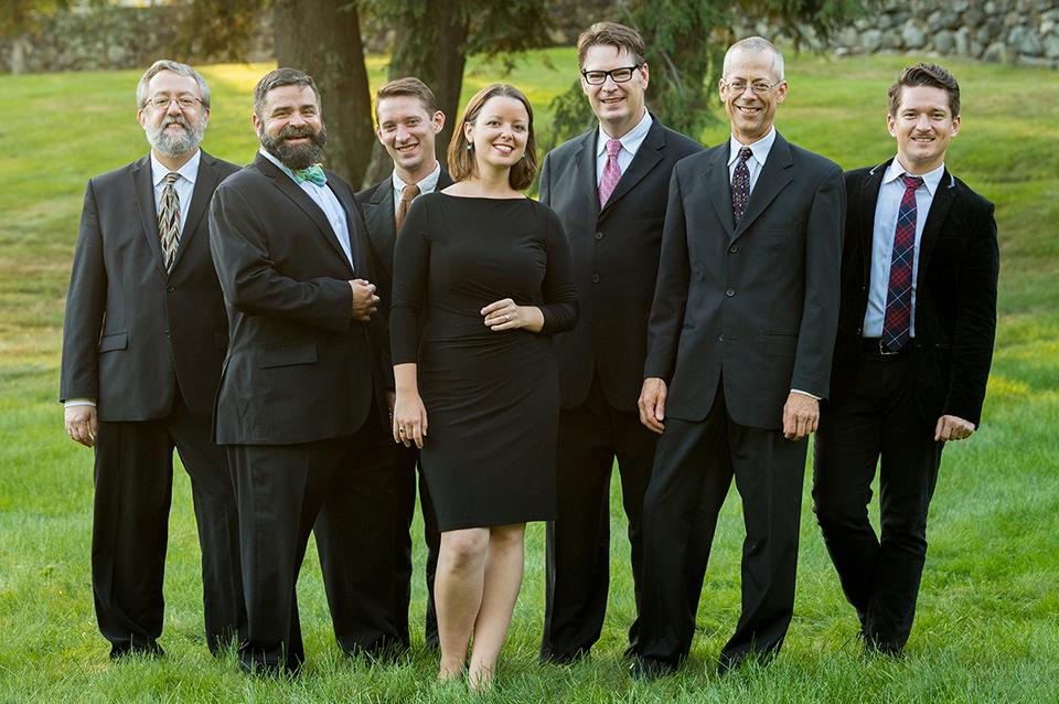 Musical group members standing in grass in suits