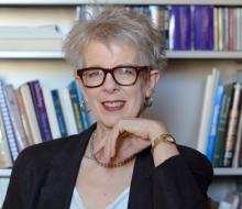 Woman with glasses pictured in front of book shelf