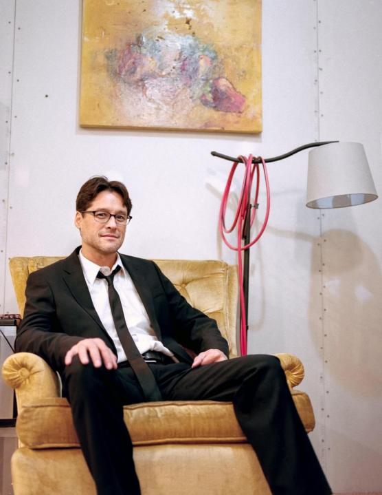 Man in dark suit sitting on gold chair