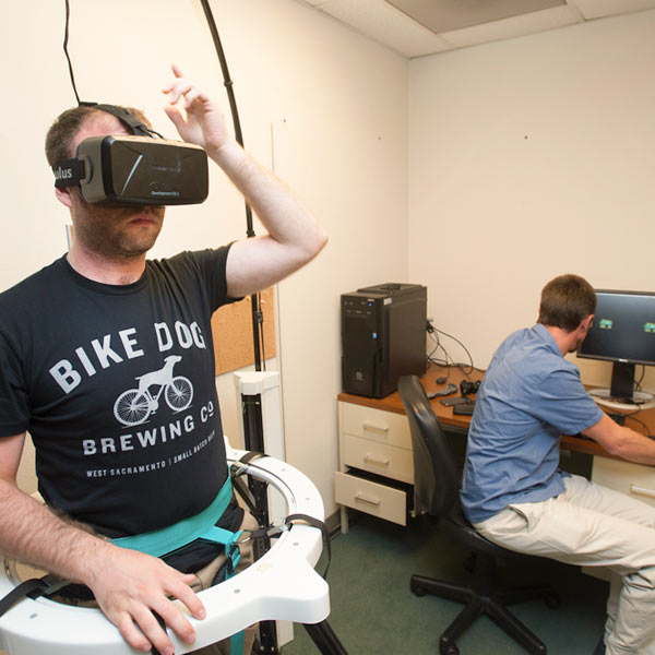 A male student wearing a virtual reality headset, explores a virtual world set up as a psychological experiment