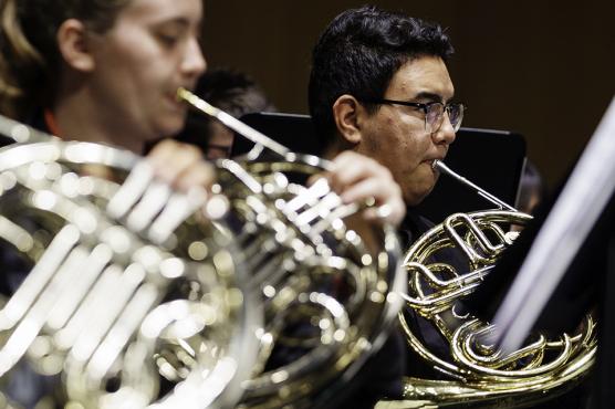 Woman playing french horn and other band member, right