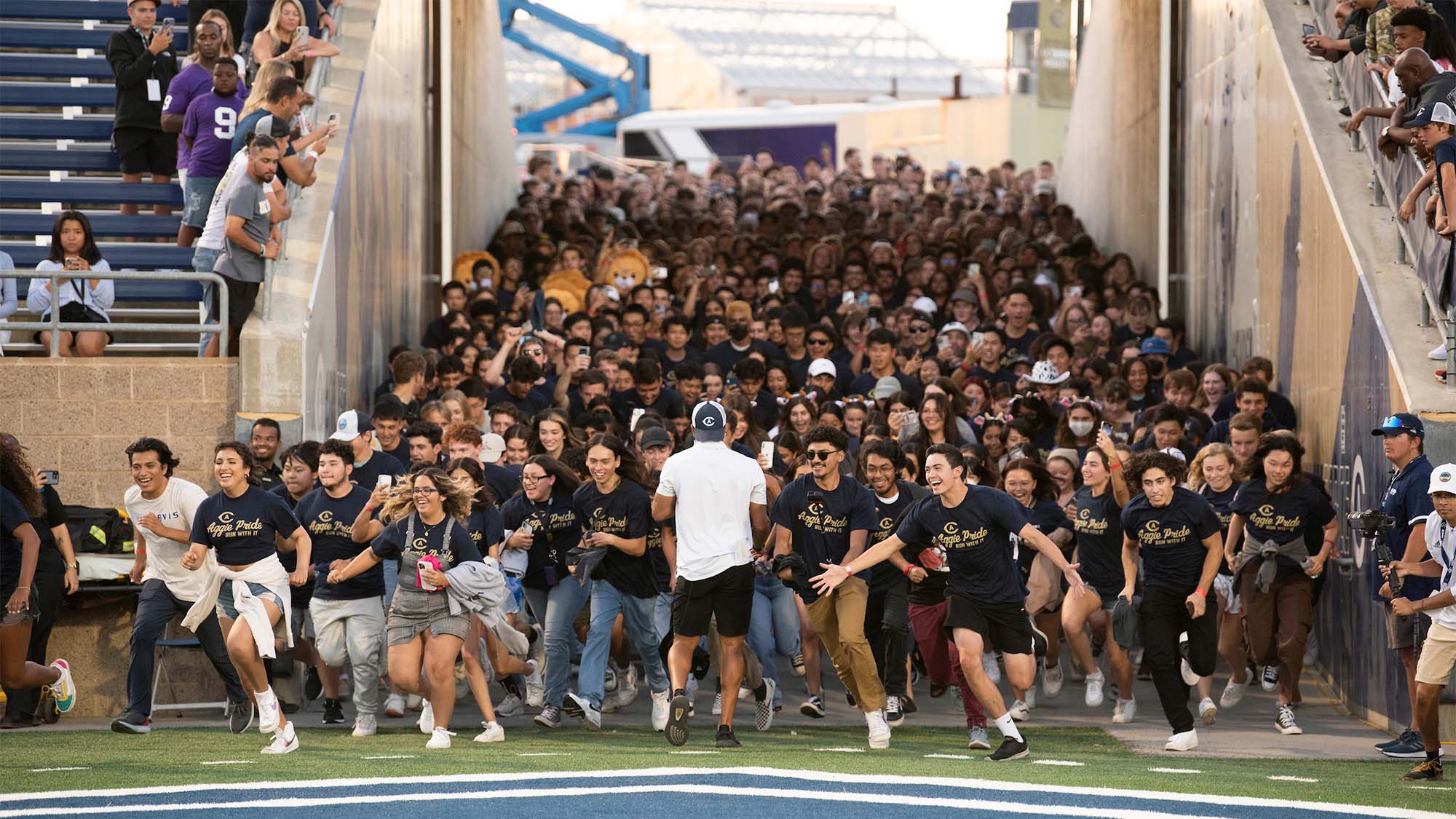 Students run onto the field at a football game.