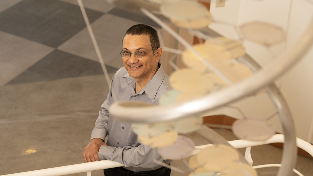 Smiling man on staircase beside DNA sculpture