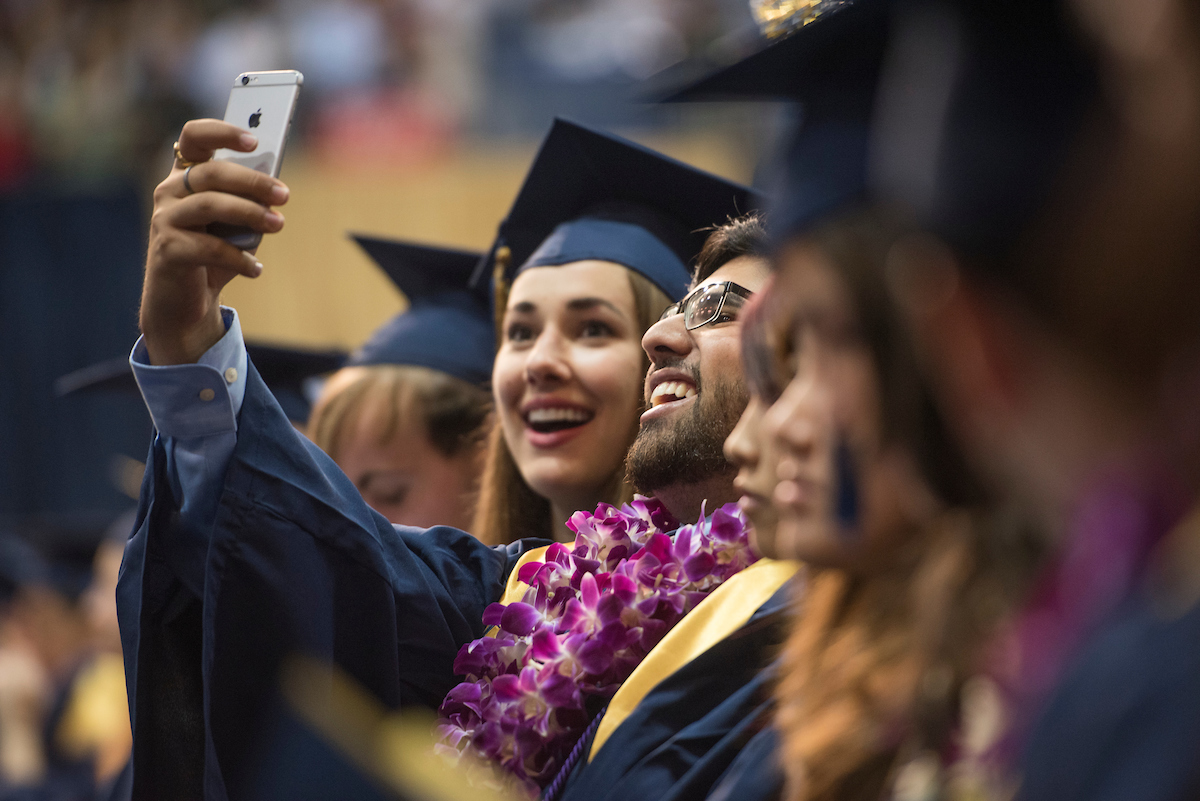 students take selfies with decorated grad caps