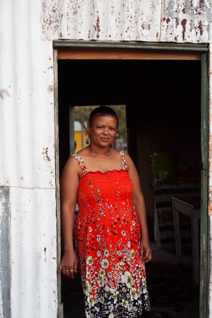 Woman standing in door way wearing bright red patterned dress