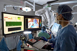 Person in lab coat, in front of computer monitors