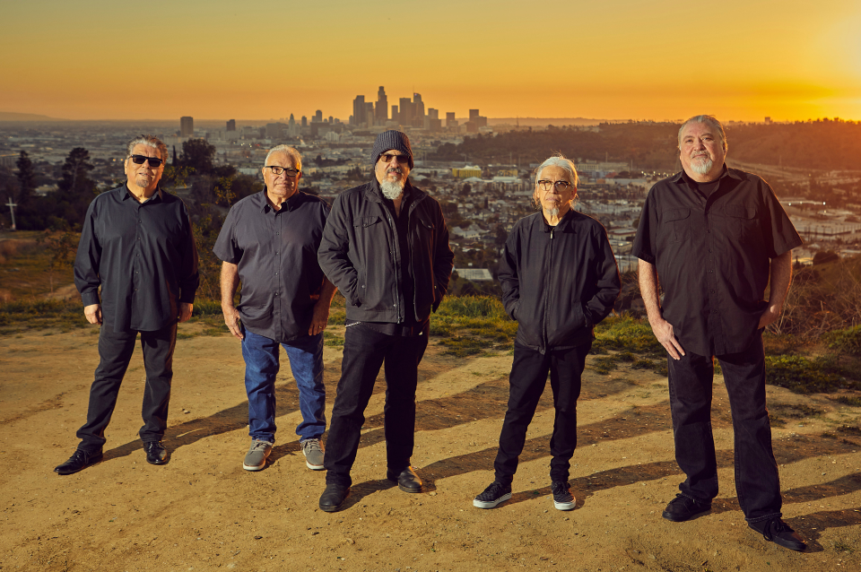 Band of men dressed in black with urban scenery behind them