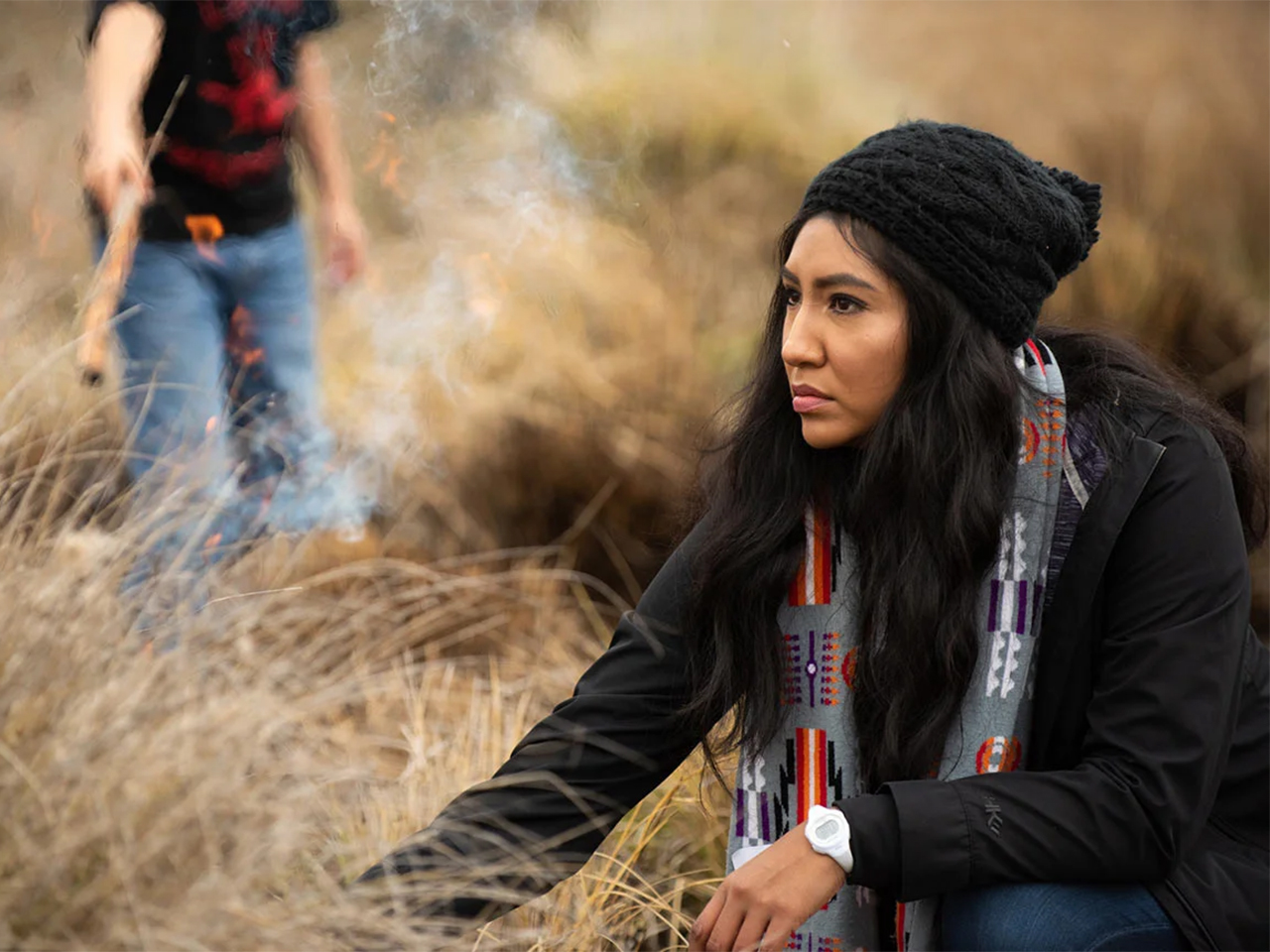 Melinda Adams crouches and lights a field of deergrass on fire
