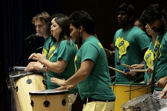 Musicians in blue shirts beating on drums