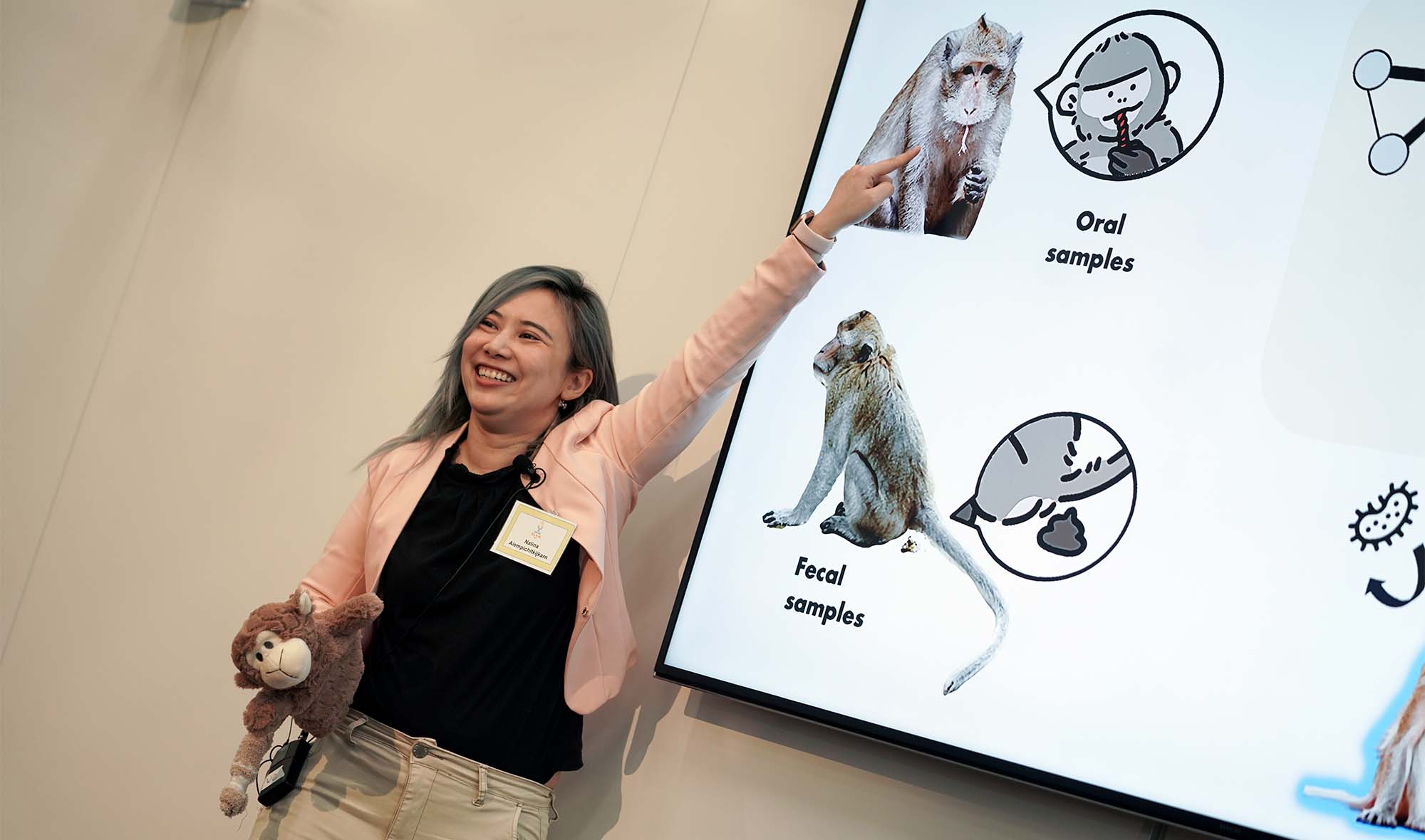 Student with plush monkey points to PowerPoint presentation.