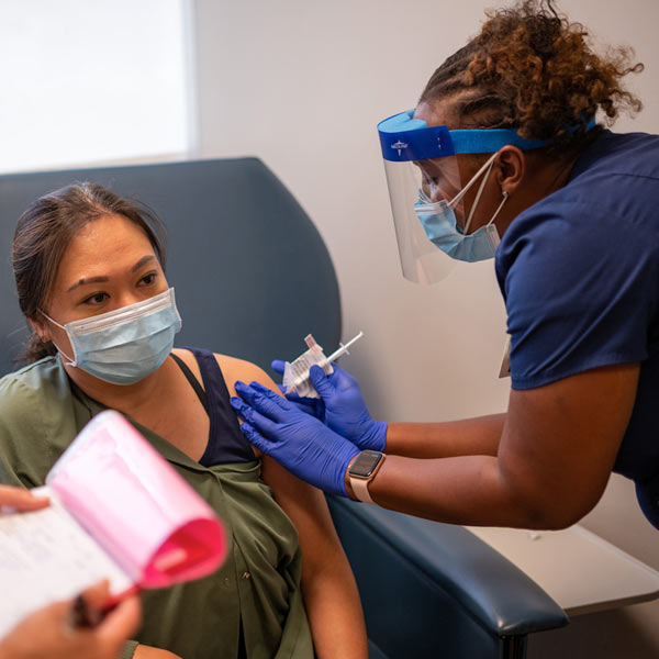 A female nurse gives a vaccination to another female