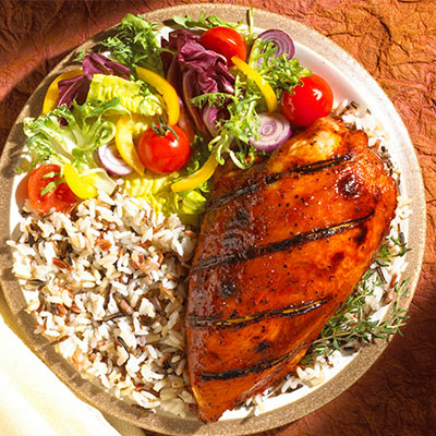 A plate with chicken, rice and a salad