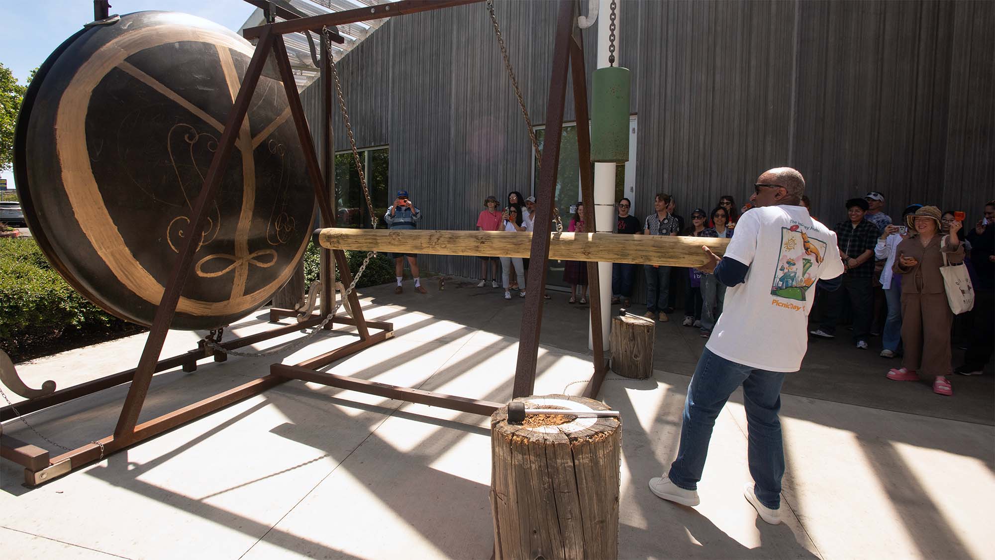 Gary S. May pulls back on the log that serves as the striker for Gong, an interactive art piece