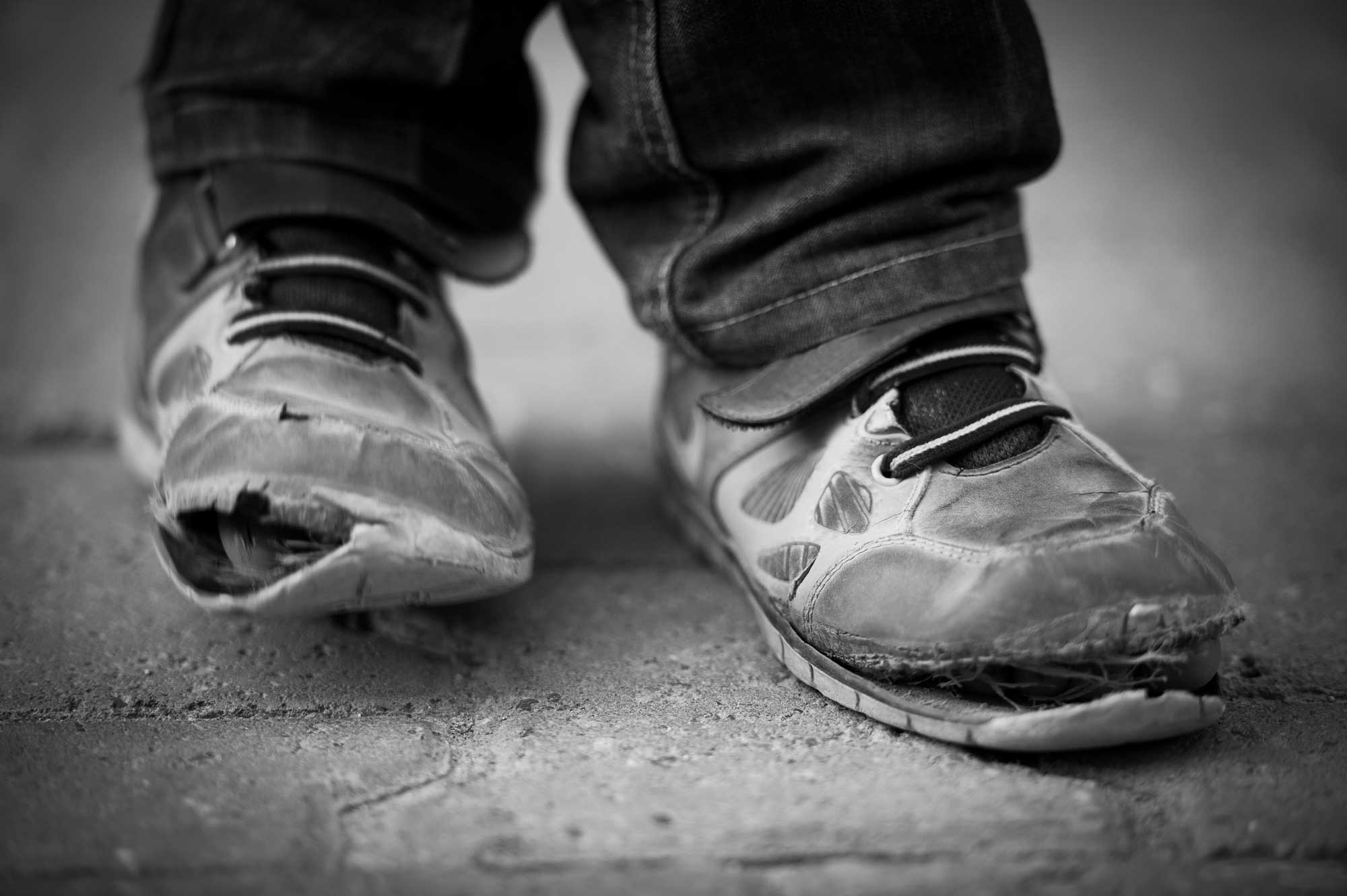 Worn out tennis shoes on feet.